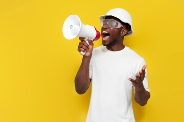 male african american builder in uniform announces information into loudspeaker on yellow background