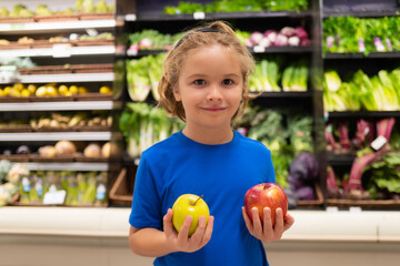 Fototapeta premium Kid with apple fruits at grocery store. Little child choosing food in grocery store or a supermarket.