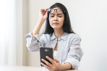 Presbyopia, Hyperopia middle aged asian woman holding eyeglasses problem with vision problem trying to read text, message from smart mobile phone screen, eye disease of old, eyesight farsightedness.