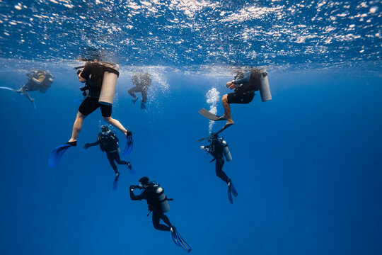 People In Dive Suit Diving Into Water