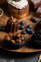 Obraz na płótnie Canvas cakes puddings and chocolate muffins with blueberries and cream cherries and slices of dried citrus on highly decorated wooden plate.