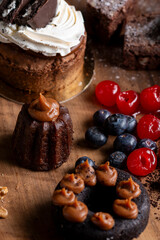 cakes puddings and chocolate muffins with blueberries and cream cherries and slices of dried citrus on highly decorated wooden plate.