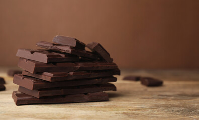 Pieces of tasty chocolate on wooden table, closeup. Space for text