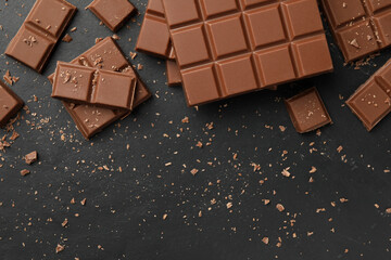 Pieces of tasty chocolate on grey table, flat lay. Space for text