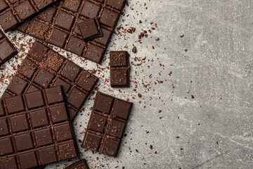 Pieces and shavings of tasty chocolate bars on light grey table, flat lay. Space for text