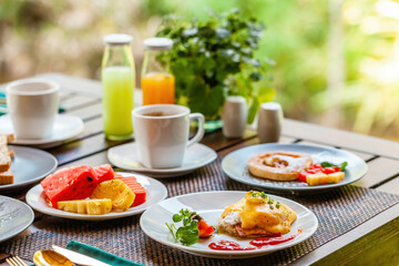 Morning breakfast table at tropical resort. Delicious and healthy meal with fresh fruit, organic eggs, and a glass of orange juice. Concept of summer vacation and a gourmet dining experience.