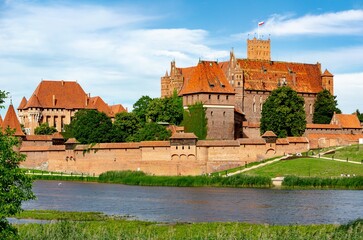 Malbork castle panorama with Nogat river, waving Polish flah and tourist