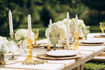 Close-up outdoor party table set up in pastel gold and white with gorgeous flower arrangements.