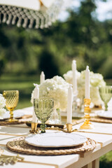 Close-up outdoor party table set up in pastel gold and white with gorgeous flower arrangements.