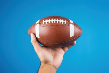 Hand holding american football ball isolated on blue background, Generative AI
