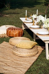 An outdoor party table arranged with exquisite flower arrangements, featuring a stunning combination of pastel gold and white decor.