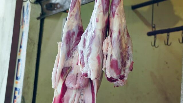 Closeup of fresh raw meat or carcasses of meat hanging in front of the meat shop