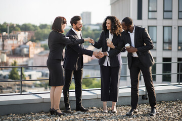 Multicultural team of specialists shaking hands and expressing satisfaction from holding efficient...