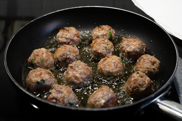 Italian (or american) meatballs spaghetti in the making and final shot. White marble background. Basil leaves on the top of the plates, with 3 meatbals on the top of the spaghetti.