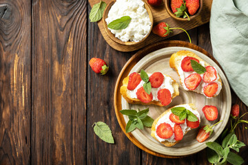 Berries toast breakfast, healthy food. Sandwich with strawberries and soft cheese on wooden background. View from above. Copy space.