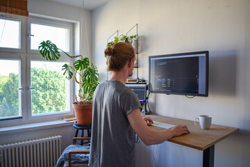 Young businessman working on stand up Desk Computer studying business ideas on a pc screen on-line.. Digital Entrepreneur Creating Modern Software, e-Commerce App Design, e-Business Coding. AI