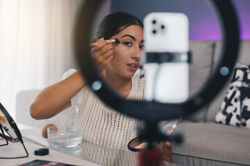 Female video blogger applying make up on face in living room