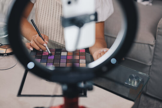 Crop female visagiste shooting makeup video tutorial