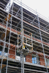 Restoration of the facade of a historic house using scaffolding with temporary elevator platform