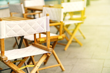 Folding wooden tables and chairs stand on the sidewalk
