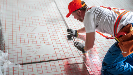 Work on underfloor heating. Sticking foil of a underfloor heating insulation. Two-in-one: EPS...