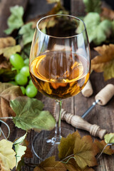 Glass of wine with grape on wooden background