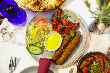 Prawn serving with salad, sauce and rolls on a dinner table.