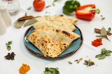Tandoori Roti or Butter Naan with tomato, cinnamon, and cardamom on a blue plate