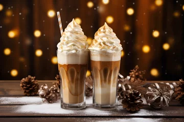 Küchenrückwand glas motiv Two tall glasses with warm coffee drink with cinnamon, whipped milk foam or cream and caramel on a kitchen table and christmas ornaments, lights and decoration. Generative AI technology © Romana