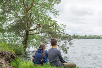 Fototapeta premium In summer, a brother and sister sit on the river bank.