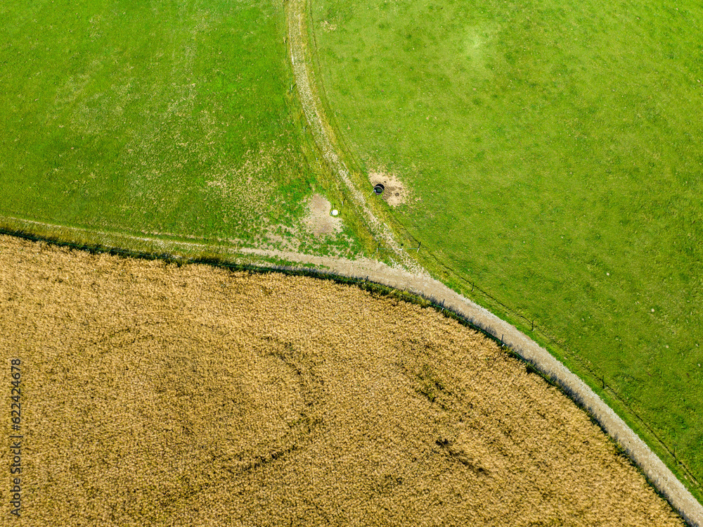 Wall mural Aerial view of countryside road through fields in rural area in Switzerland.