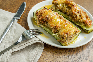 Homemade baked zucchini, stuffed with meat on a plate on the wooden table