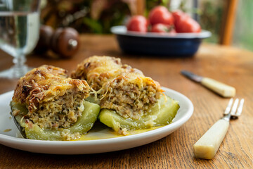 Stuffed zucchini, baked with meat, onions, herbs and cheese on the wooden table