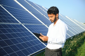 Portrait young indian technician or manager wearing formal cloths standing with solar panel....