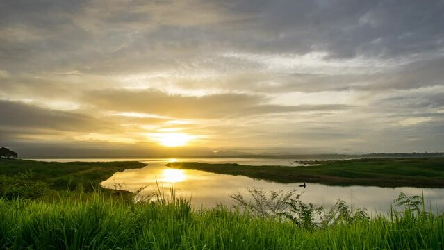 Timelapse Sunset over the reservoir, orange light in the evening on a cloudy day.