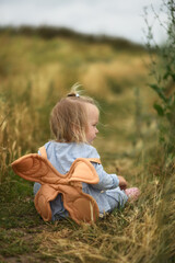 Little beautiful girl  with backpack is walking in the field