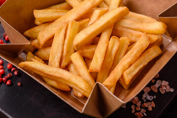 Delicious crispy french fries with salt and spices in a cardboard box