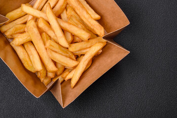 Delicious crispy french fries with salt and spices in a cardboard box