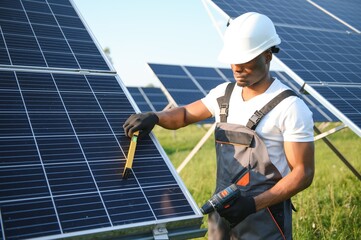 African American engineer maintaining solar cell panels. Technician working outdoor on ecological...