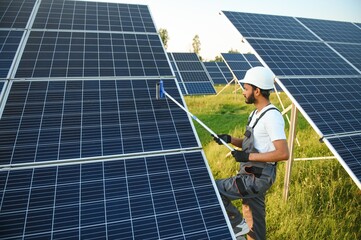 Indian handyman cleaning solar panels form dust and dirt.