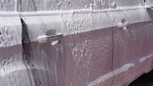 Washing a car with white foam. High pressure lance that spreads foam. Wash gun snow foam lance