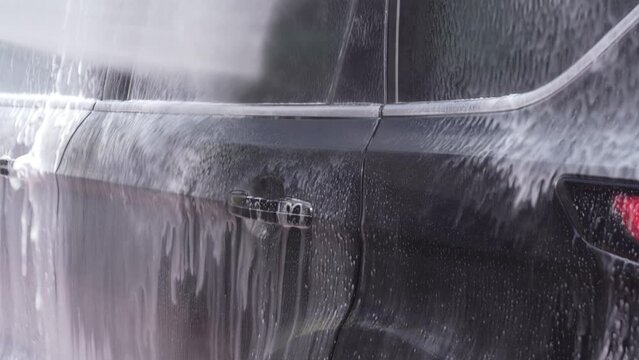 Washing a car with white foam. High pressure lance that spreads foam. Wash gun snow foam lance