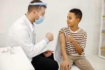 Obraz premium Male doctor stick a band-aid to a boy after a vaccination