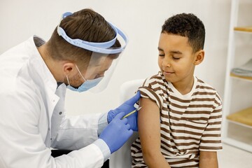 Obraz premium Male doctor doing a vaccination to a multiracional boy