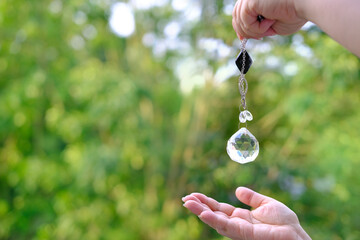 Woman hand holding and using glass ball crystal ball pendulum and using, female hands with crystal...