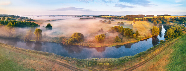 Aerial view of rural landscape with river and lush trees in fog