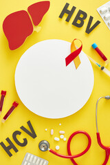 International Hepatitis Day. Top view of paper liver, tablets, stethoscope, HBV, HCV abbreviation, awareness ribbon, blood samples and syringe on yellow background with blank circle for text