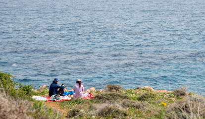 Fototapeta premium Young couple doing picnic by the sea. People relaxing outdoors