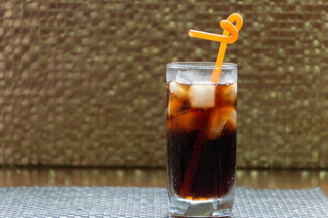 In a glass of dark soda with ice and a straw