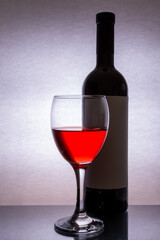 On the table is a bottle and a glass of red wine